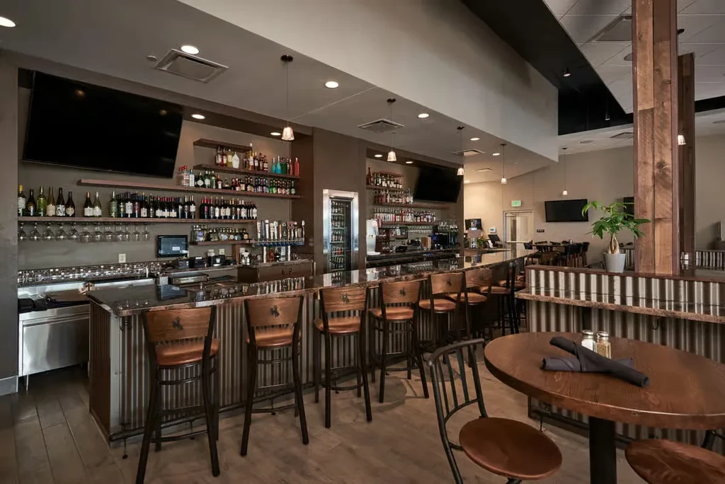Well-stocked modern bar with corrugated metal and wooden seating.