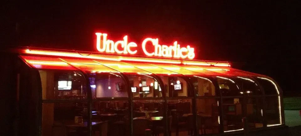 Uncle Charlie's exterior at night, with curved glass and red neon signs.