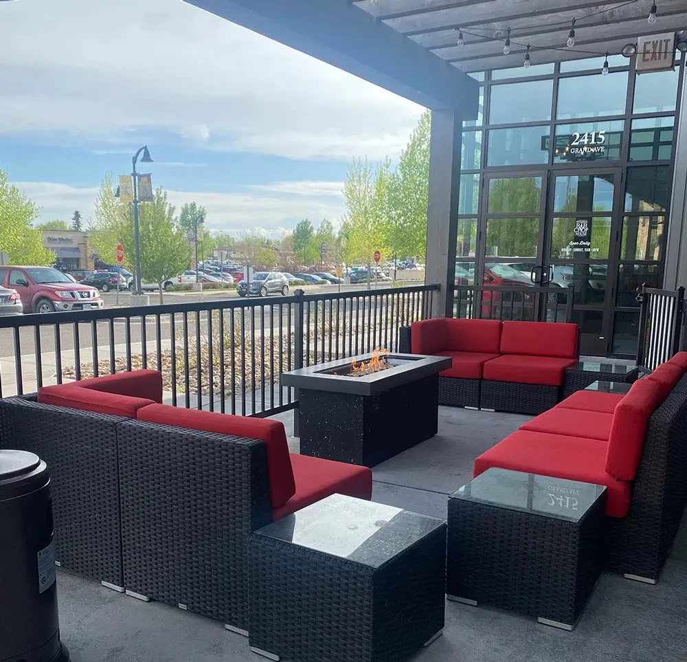 Restaurant patio with red-cushioned sectionals, a fire pit, and string lights.