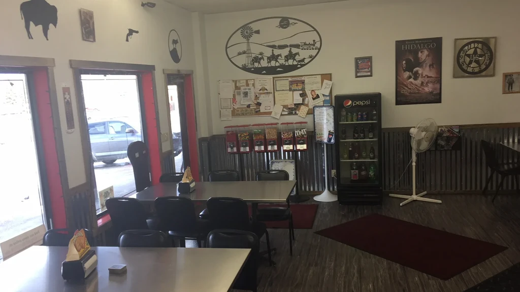 Empty Western-themed diner interior with tables, snack machines, and community board.