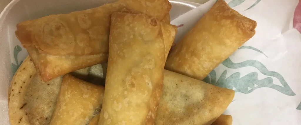 Golden-brown fried pastries and rolls in a take-out container.