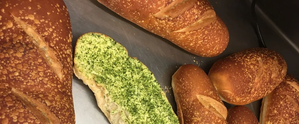 Golden-brown loaves of bread with slashes and garlic bread.