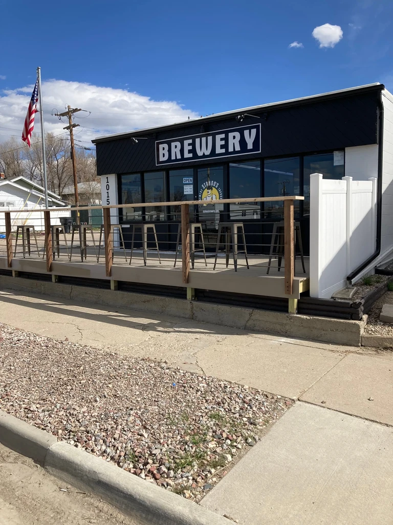 Dark modern brewery, "BREWERY" sign, outdoor patio, and American flag.