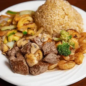 Plate of fried rice, steak, shrimp, and stir-fried vegetables.