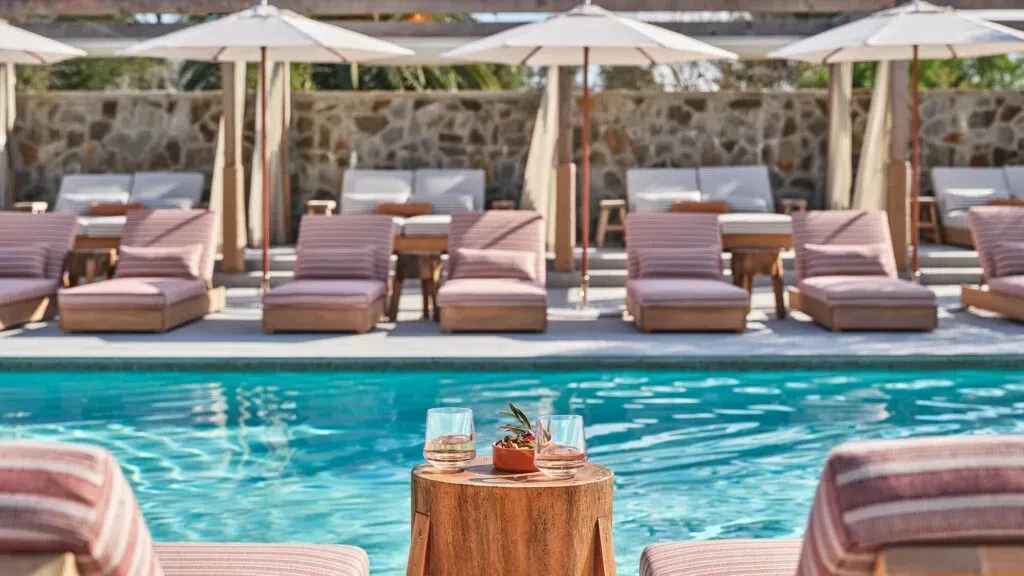 Drinks and appetizer on wooden stump table by resort pool.