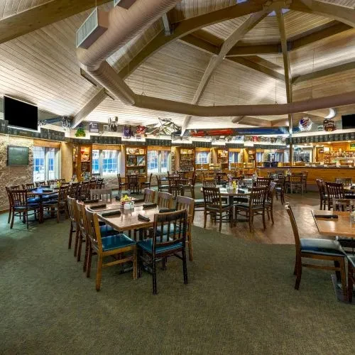 Empty rustic restaurant interior with vaulted wood ceiling and bar.