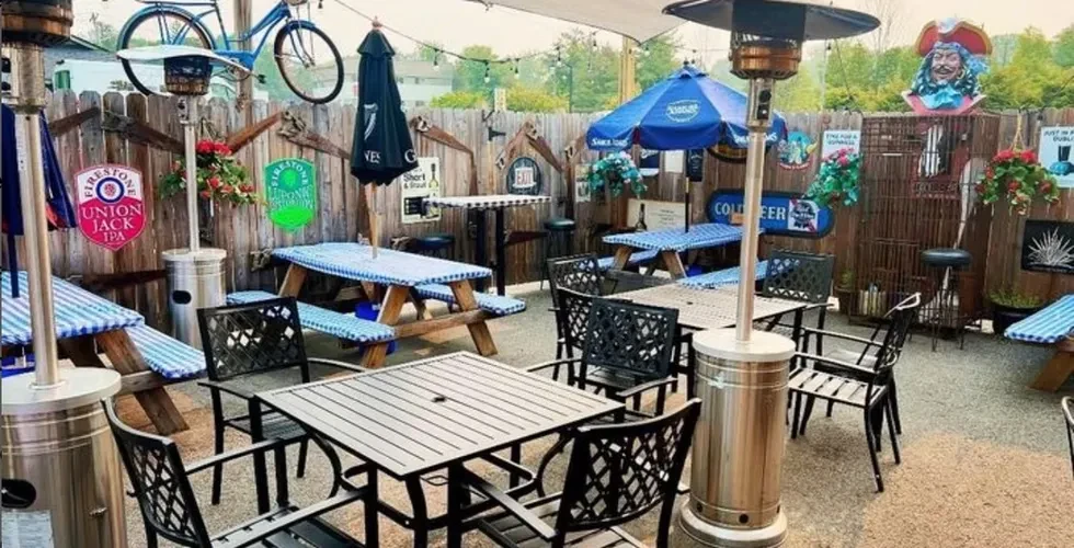 Rustic outdoor beer garden with empty tables, heaters, and eclectic decor.