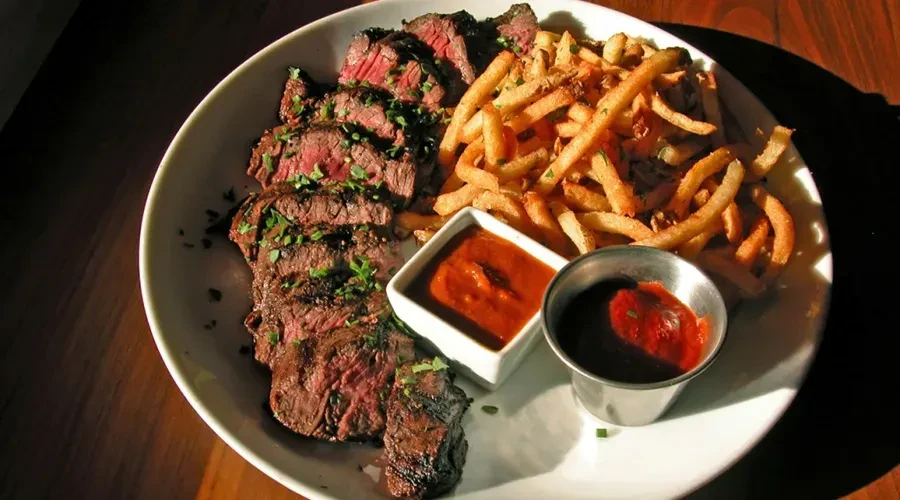 Sliced grilled steak frites with herbs and two sauces.