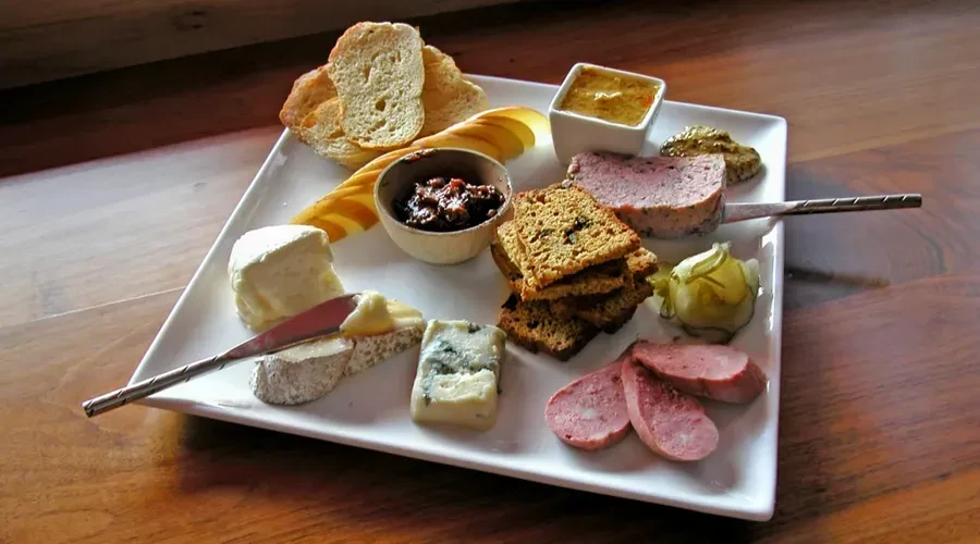 Gourmet charcuterie and cheese board with bread, meats, cheeses, and fruit.