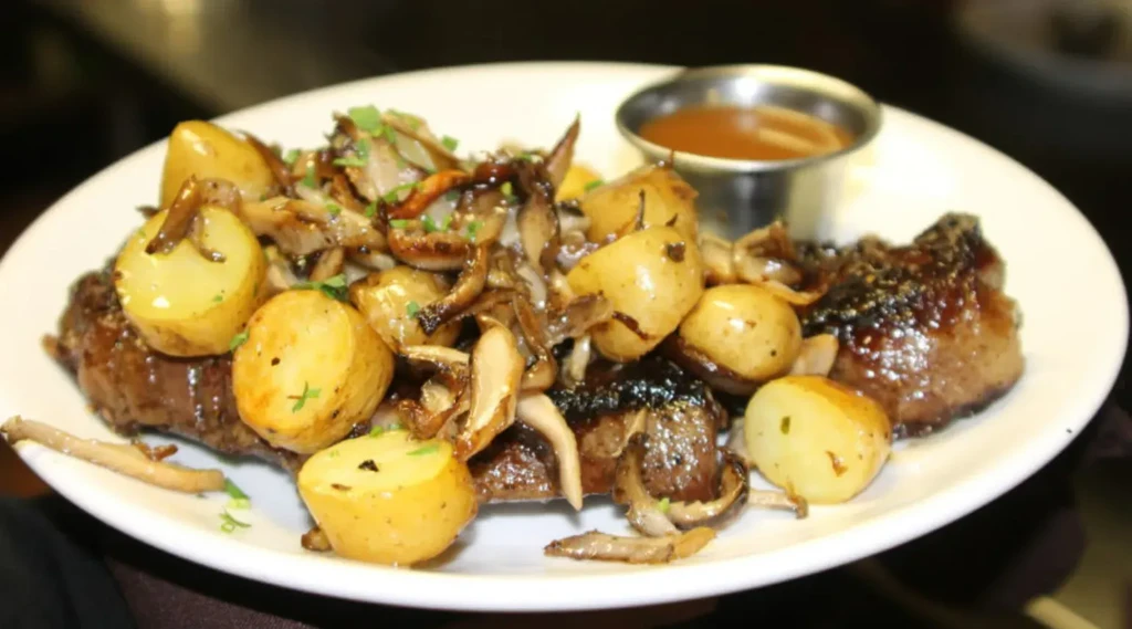 Seared steak with roasted potatoes, mushrooms, and a brown sauce.