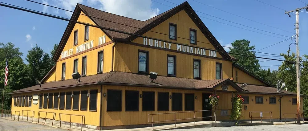 Two-story Hurley Mountain Inn with yellow siding and brown roof.