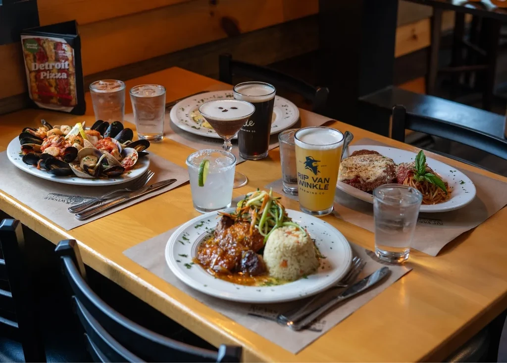 Restaurant table filled with seafood, beers, cocktails, and entrees.