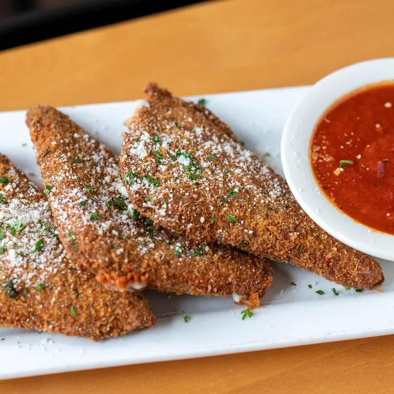 Four fried triangular appetizers with Parmesan, herbs, and marinara sauce.