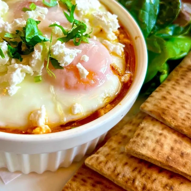Baked eggs in tomato sauce with feta, herbs, and flatbread.