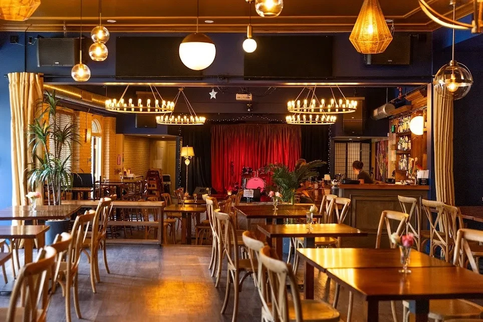 Restaurant interior with dining tables, a bar, and a performance stage.