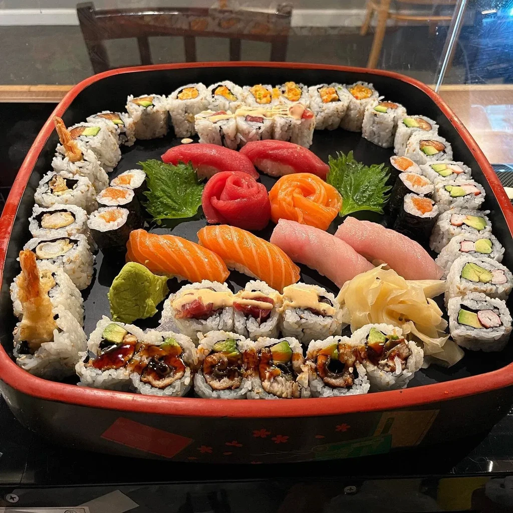 Vibrant platter of assorted sushi, sashimi, and rose-shaped tuna and salmon.