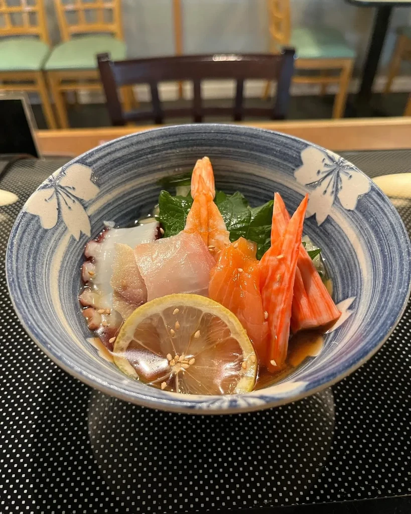 Colorful seafood bowl with shrimp, salmon, octopus, and lemon.