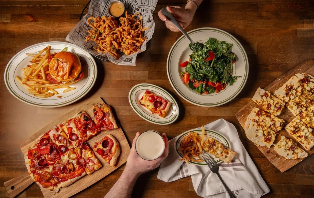 An overhead shot of several restaurant dishes and drinks on a wooden table.