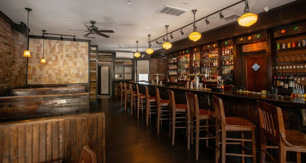 An empty bar and restaurant with wooden furnishings and a brick wall.