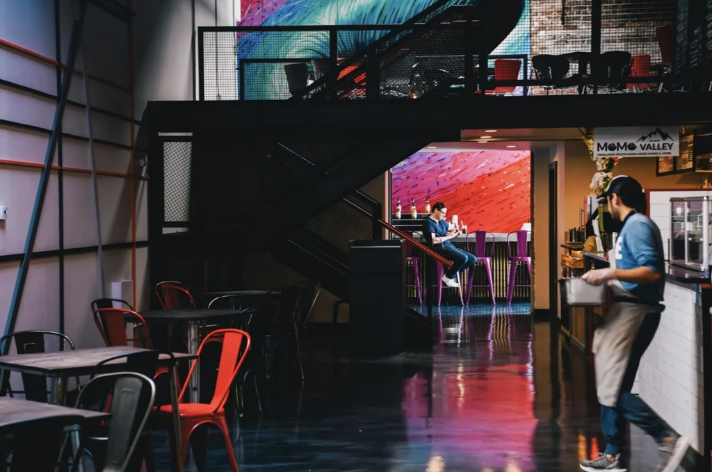 A coffee shop with a man working and a customer at a bar.