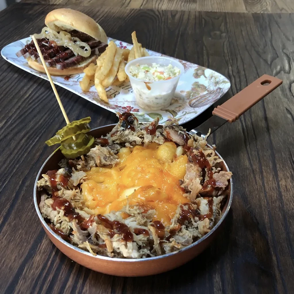 Barbecue brisket sandwich, fries, coleslaw, and a skillet of mac and cheese.