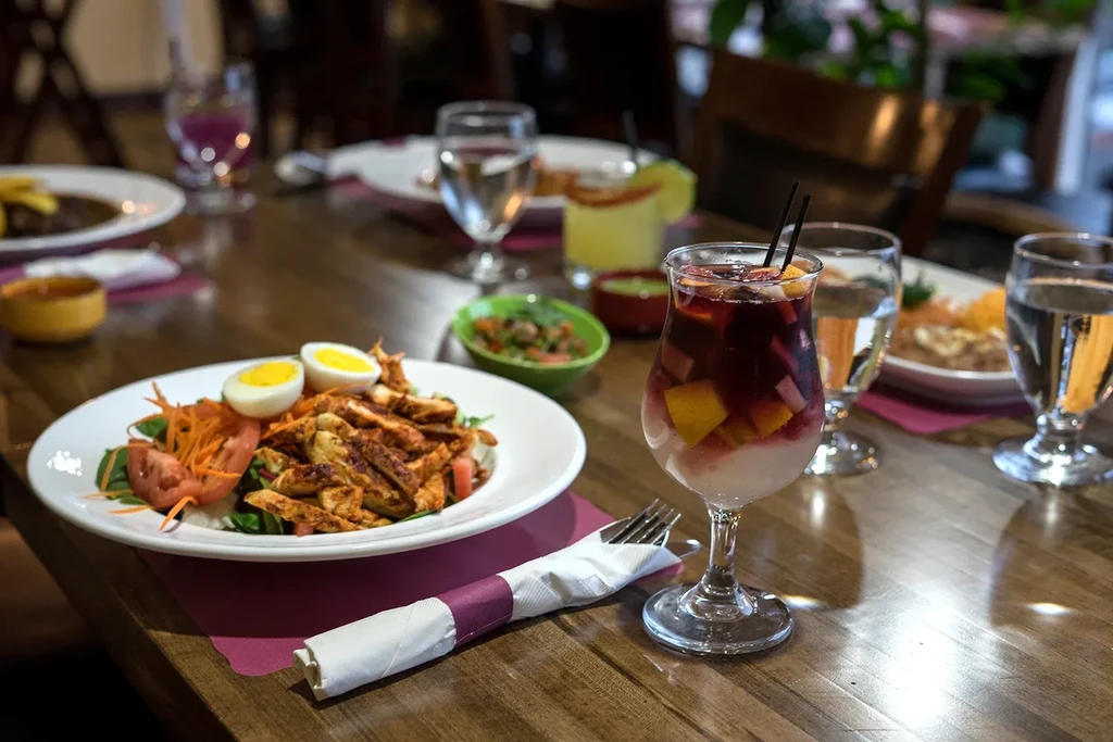 A restaurant table with a salad, sangria, and water glasses.