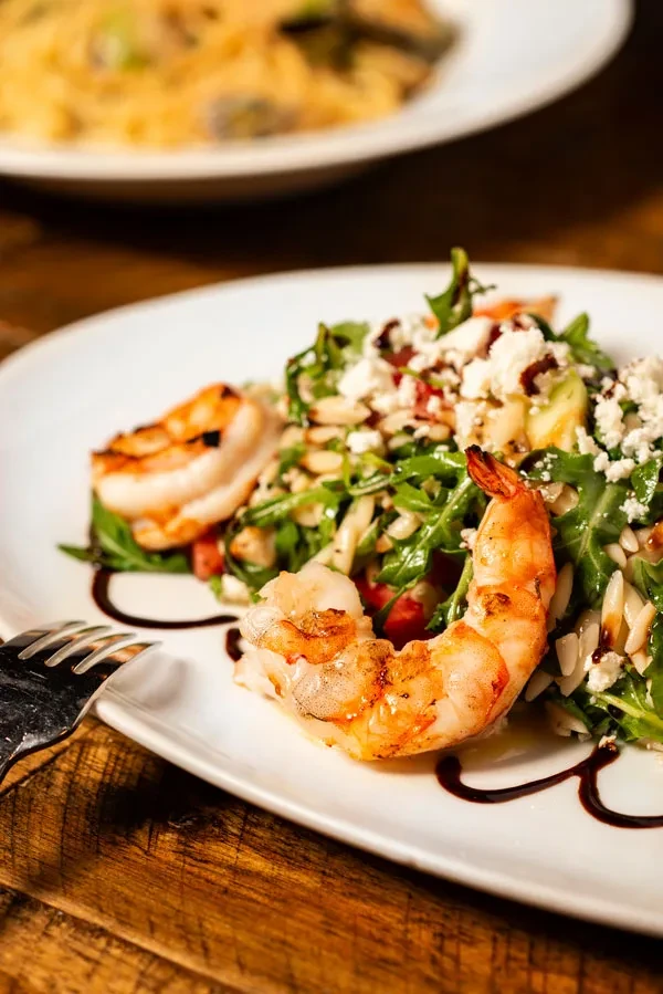 Grilled shrimp salad with feta cheese, arugula, and balsamic glaze.