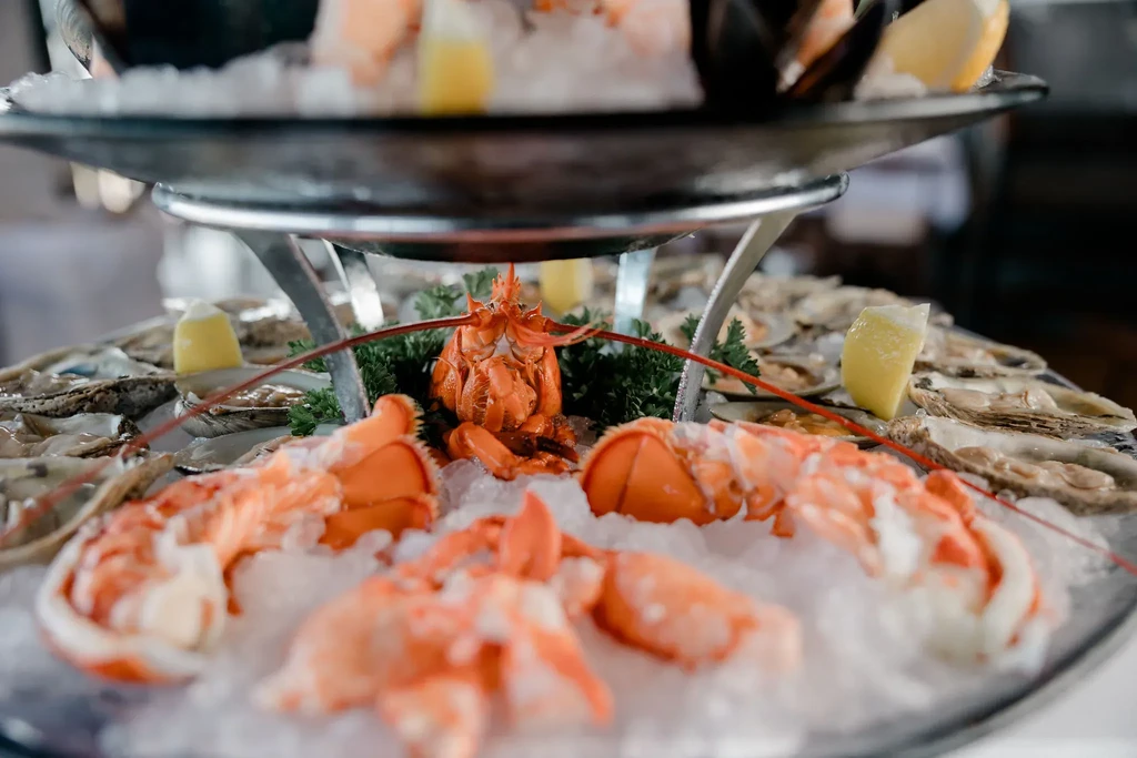 A two-tier seafood tower with lobster, oysters, and lemon wedges.