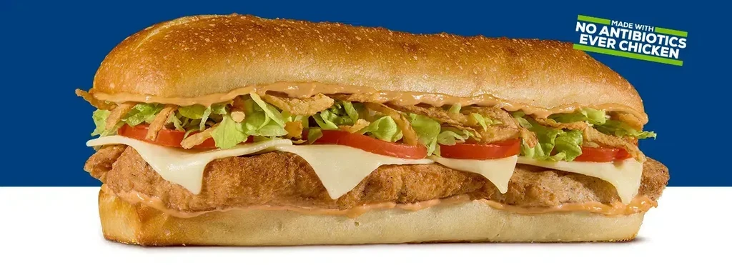 Crispy chicken sandwich with cheese, lettuce, tomato, sauce on a sub bun.