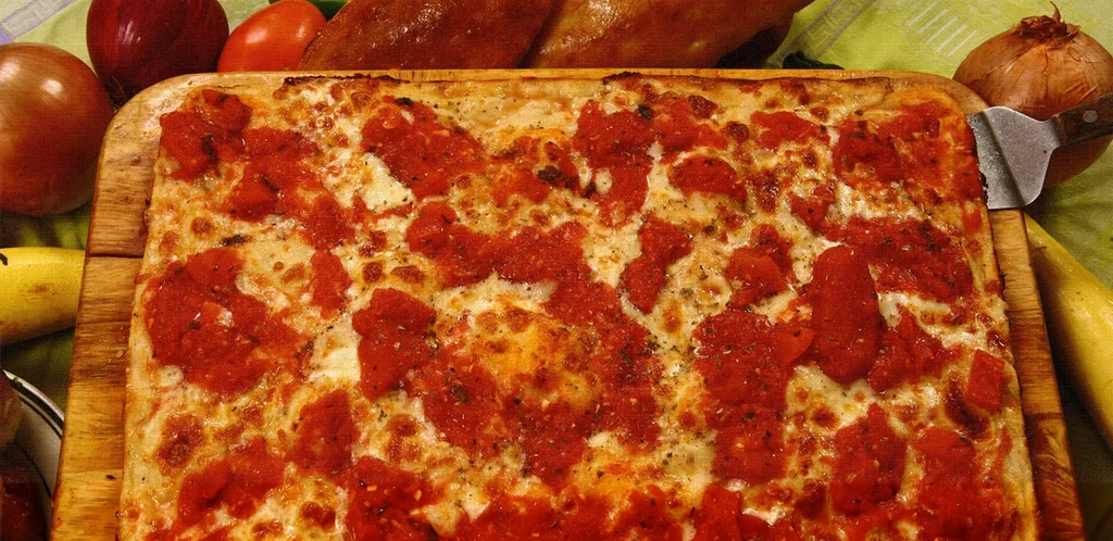 A rectangular tomato and cheese pizza on a wooden board.