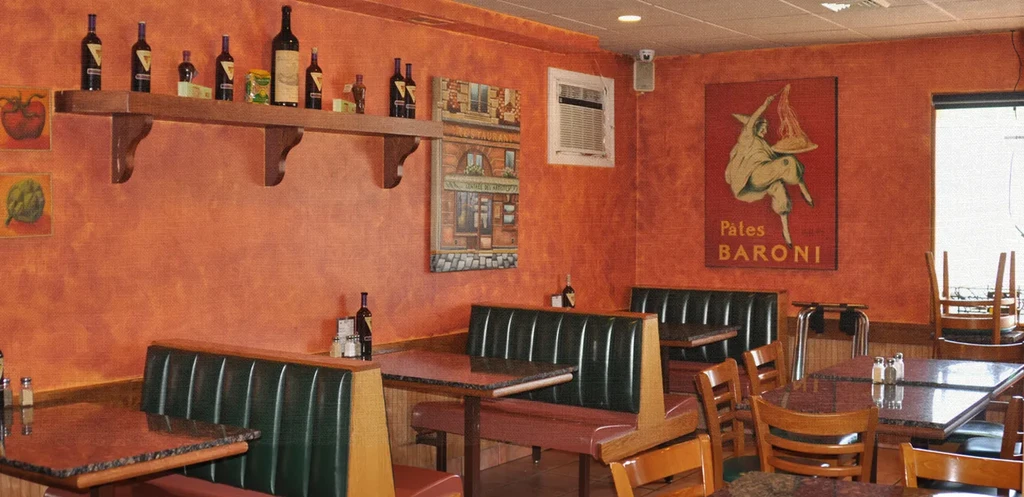 Italian restaurant interior with rustic orange walls and dark green booths.