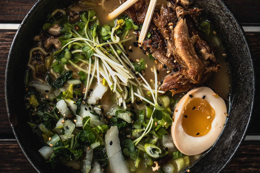 Close-up of a bowl of ramen with meat, egg, and vegetables.