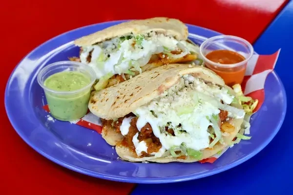 Two stuffed flatbreads with lettuce, cheese, and sauce on a purple plate.