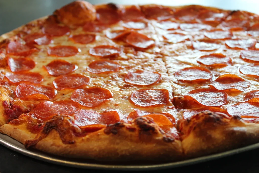 Close-up of a pepperoni pizza with bubbly cheese on a silver tray.