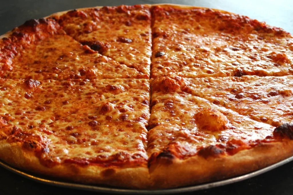 Hot, bubbly mozzarella cheese pizza, sliced into eight pieces on a pan.