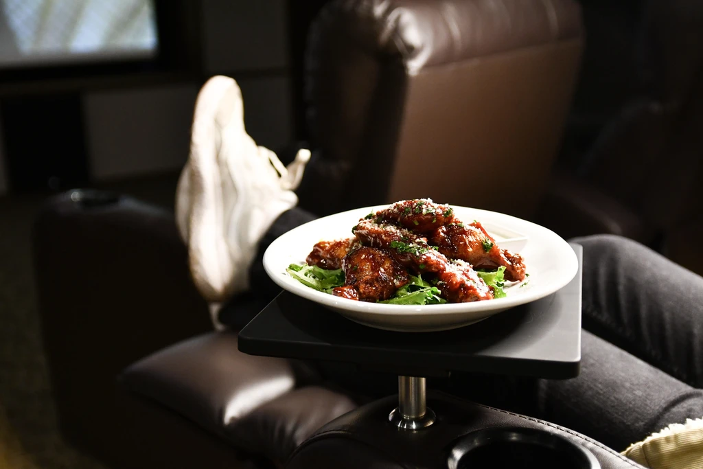 Glossy chicken wings with herbs and cheese on a recliner table.