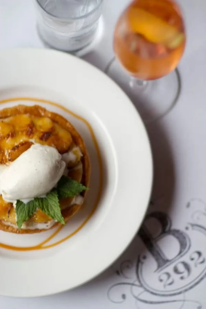 Dessert tart with ice cream, mint, and caramel swirl. Drink in background.
