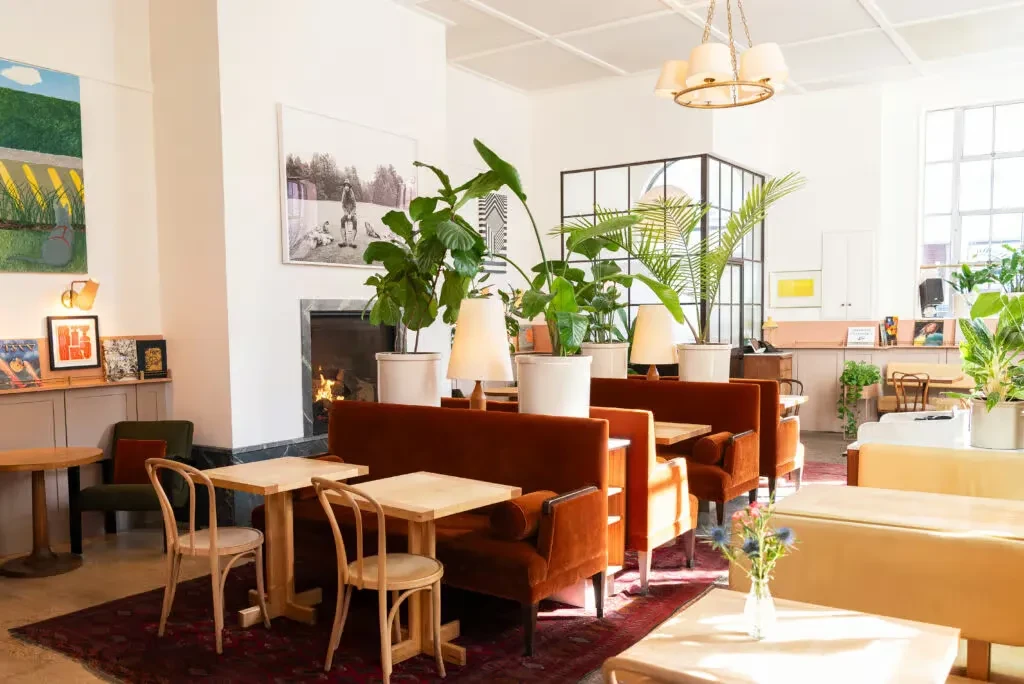 Modern restaurant with orange velvet booths, fireplace, and natural light.