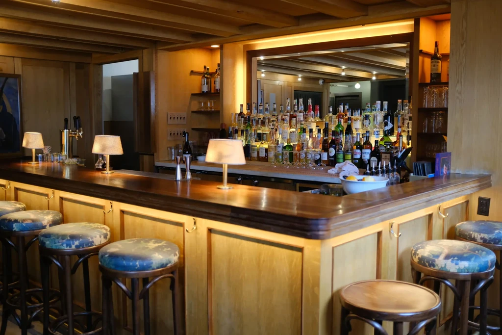 Warm wooden bar interior with extensive liquor bottles and bar stools.