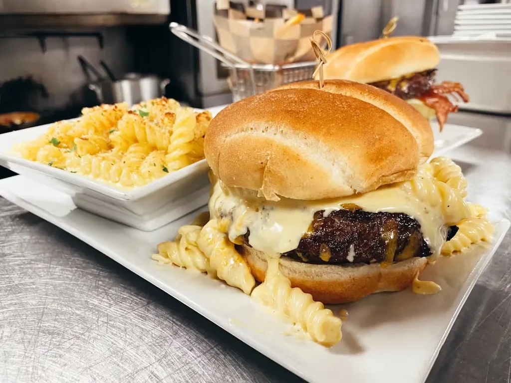 Two cheeseburgers and mac and cheese on a stainless steel surface.
