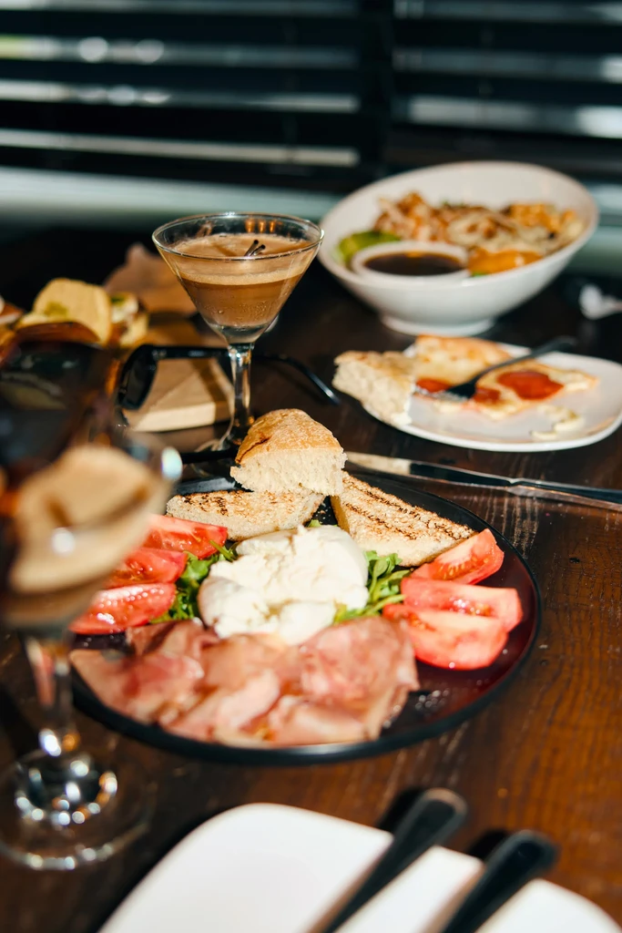 A table set with Italian appetizers, a martini glass, and a main course.