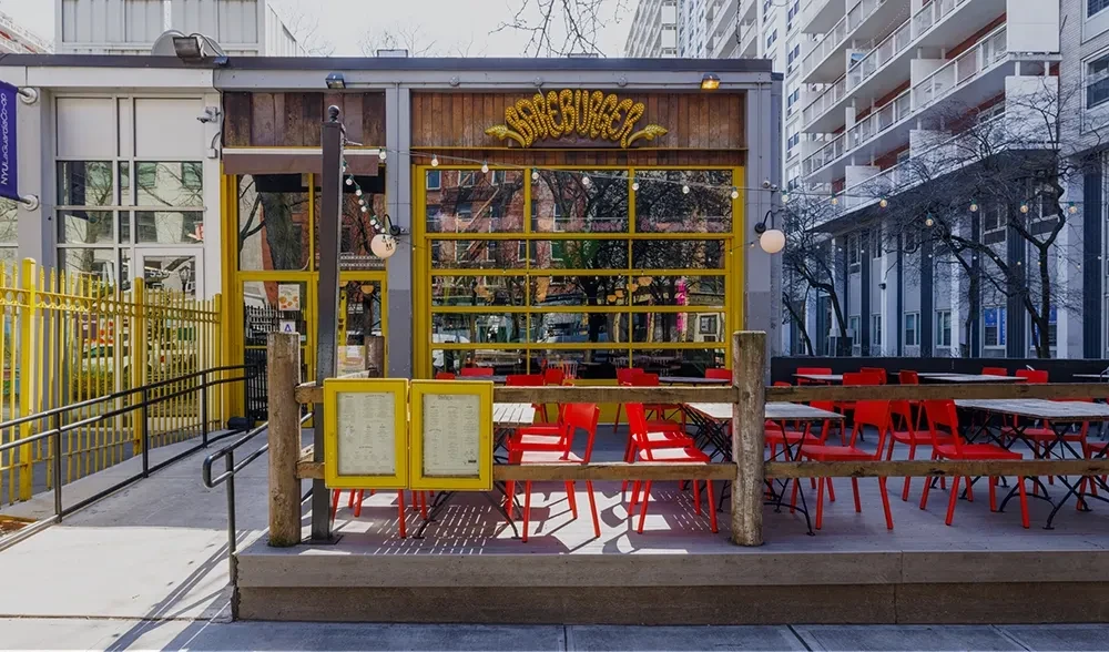 Bareburger restaurant with yellow-framed facade and red-chaired outdoor patio.