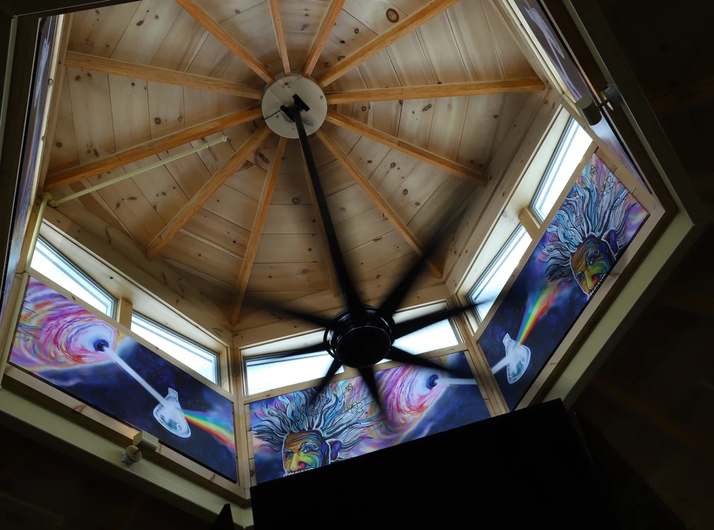 Octagonal wooden ceiling, moving fan, and vibrant art panels featuring Einstein.
