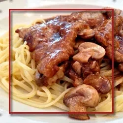 Pork cutlets and mushrooms in a sauce, served over spaghetti.