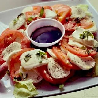 A Caprese salad with mozzarella, tomatoes, balsamic glaze, and basil.