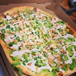 A pizza with chicken, lettuce, and a white sauce in a box.