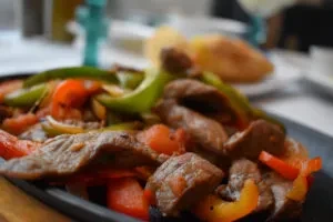 Sizzling platter of beef fajitas with peppers and onions.