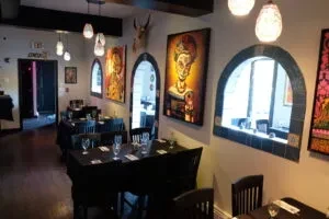 An empty Mexican restaurant with arched windows and colorful art on the walls.