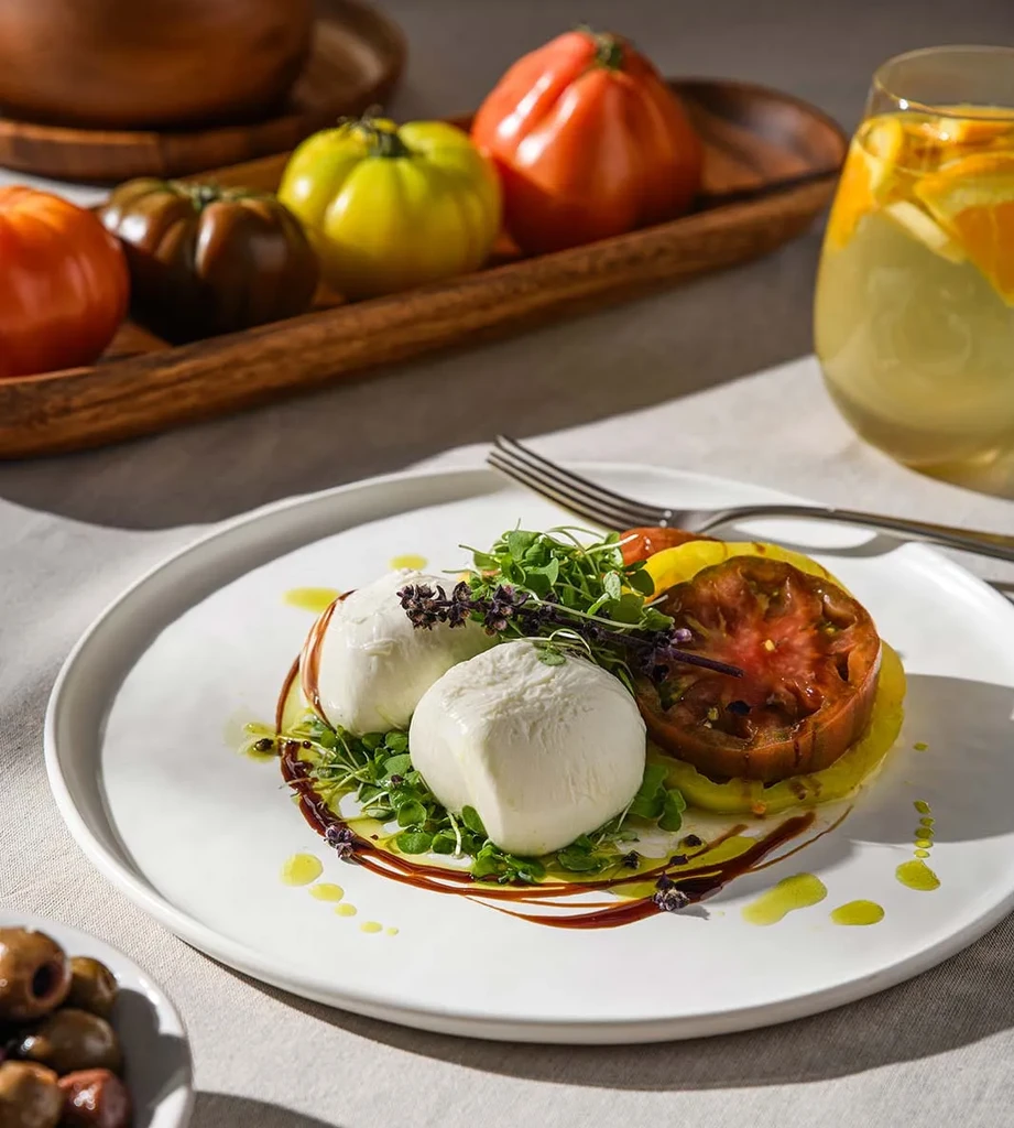 Caprese salad with sliced heirloom tomatoes, mozzarella, and microgreens.
