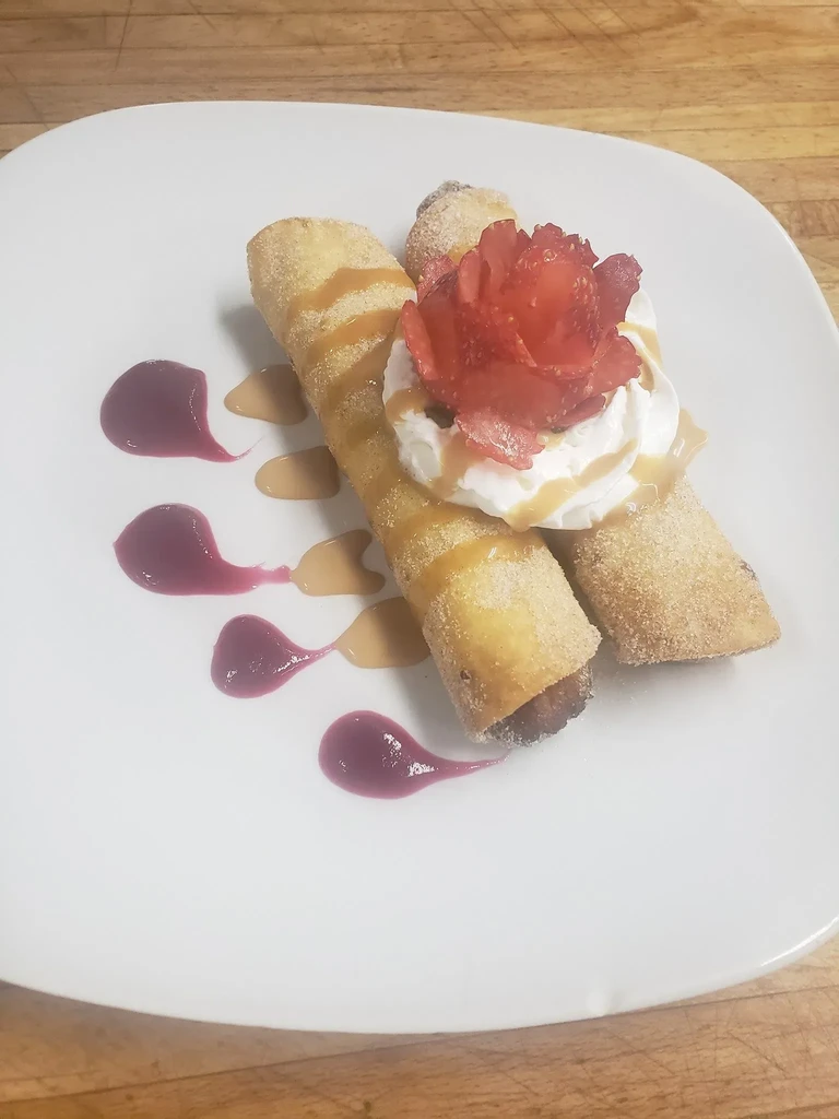 Dessert plate: fried pastries, whipped cream, strawberry rose, and caramel sauce.